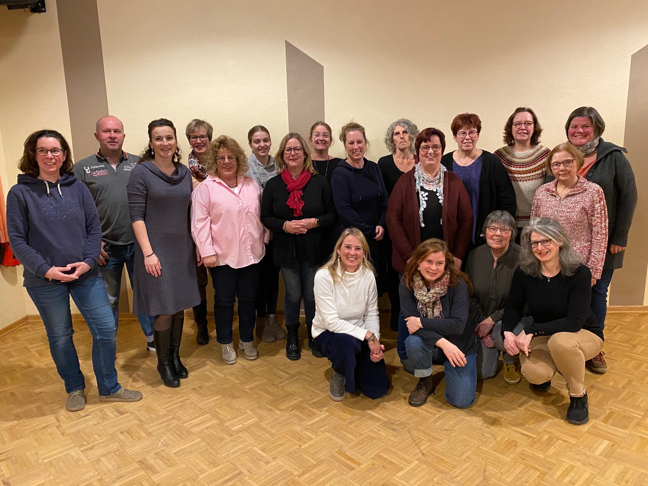 Gruppenbild der Sängerinnen des Chores Cantastic mit Chorleiter; alle stehen locker entspannt in Probenraum und lächeln in die Kamera.